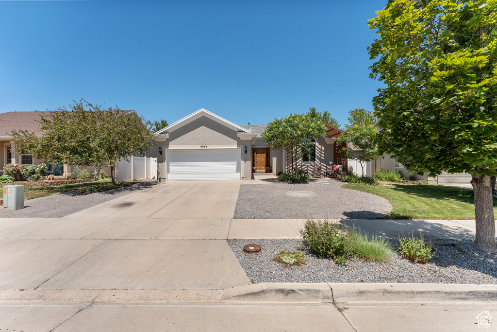 View of front facade featuring driveway, stucco siding, and a garage
