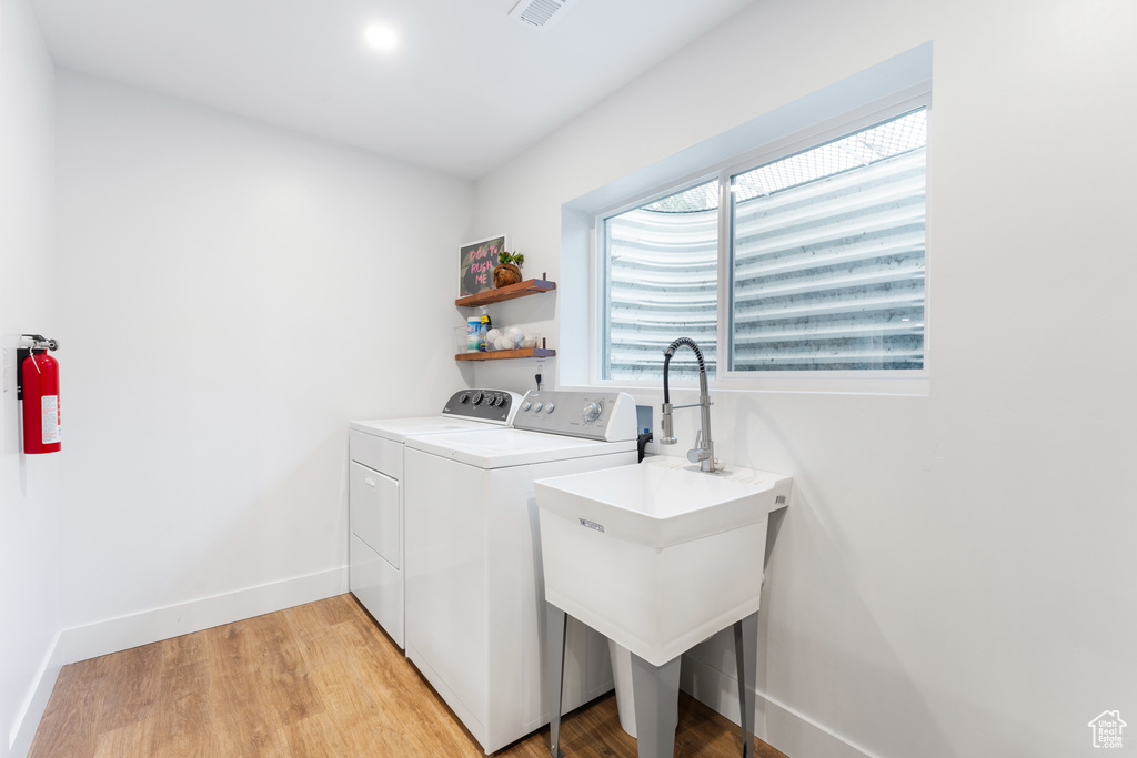 Laundry area with washer and clothes dryer and light wood-style flooring