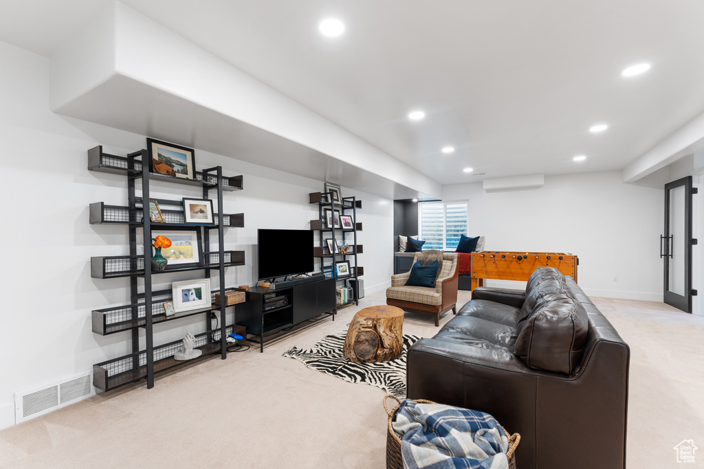Carpeted living area featuring a wall mounted air conditioner and recessed lighting