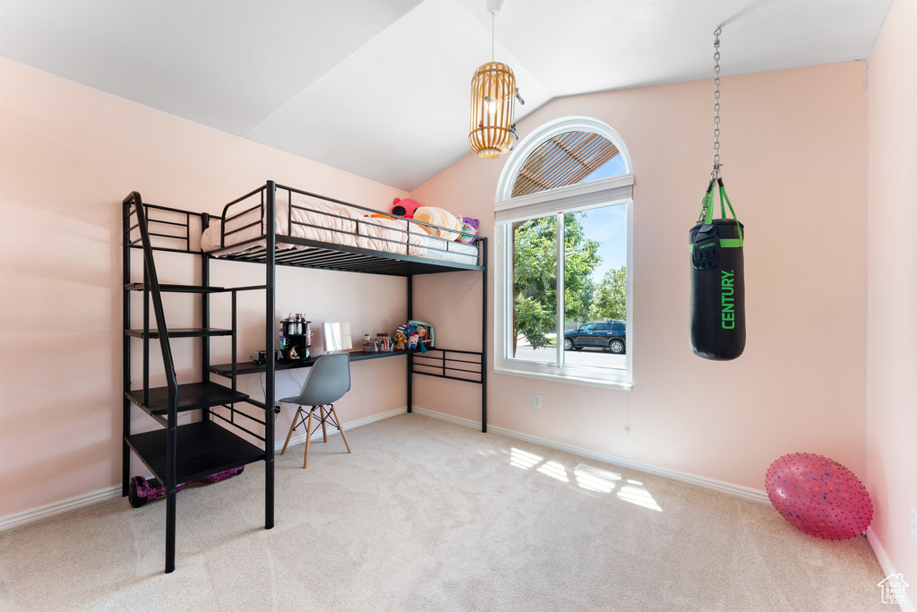 Carpeted bedroom featuring lofted ceiling and a chandelier