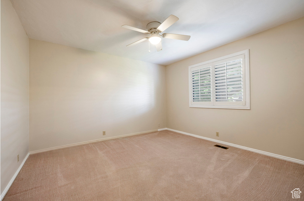 Empty room with light carpet and a ceiling fan