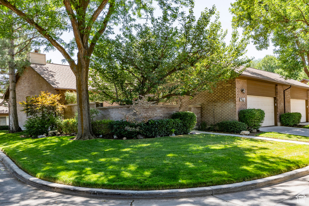View of side of property featuring brick siding, a lawn, a garage, and a chimney