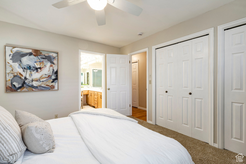 Carpeted bedroom featuring ceiling fan and ensuite bath