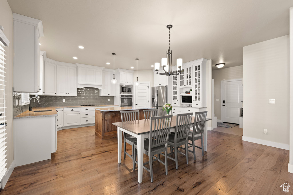 Kitchen featuring stainless steel appliances, a kitchen island, a chandelier, white cabinets, and recessed lighting