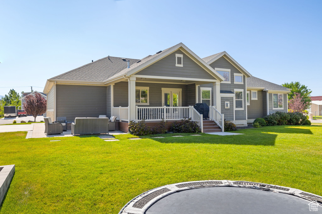 View of front of house with an outdoor living space, covered porch, a front lawn, and a shingled roof