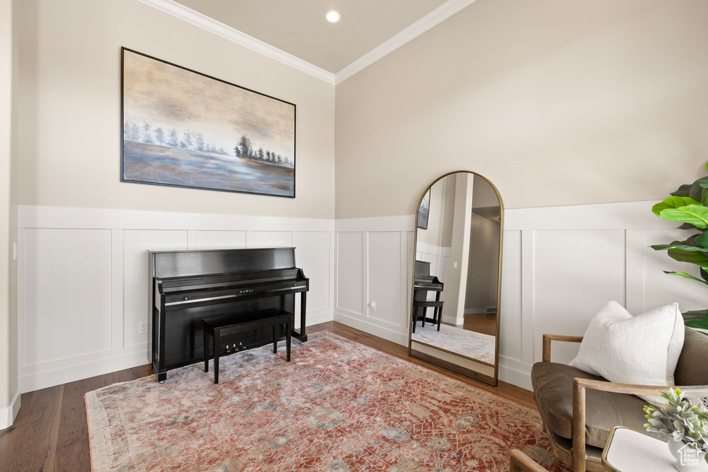 Sitting room featuring a decorative wall, crown molding, wood finished floors, a wainscoted wall, and arched walkways