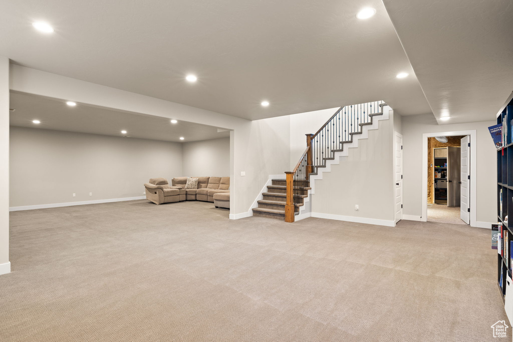 Unfurnished living room featuring light carpet, stairway, and recessed lighting