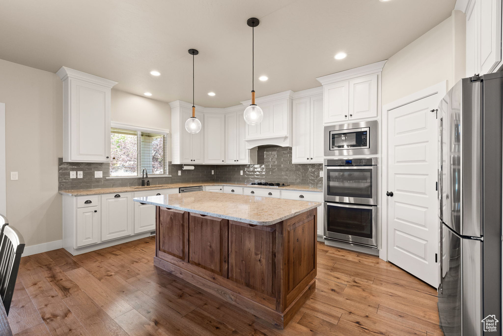 Kitchen featuring appliances with stainless steel finishes, white cabinetry, light wood-type flooring, backsplash, and recessed lighting