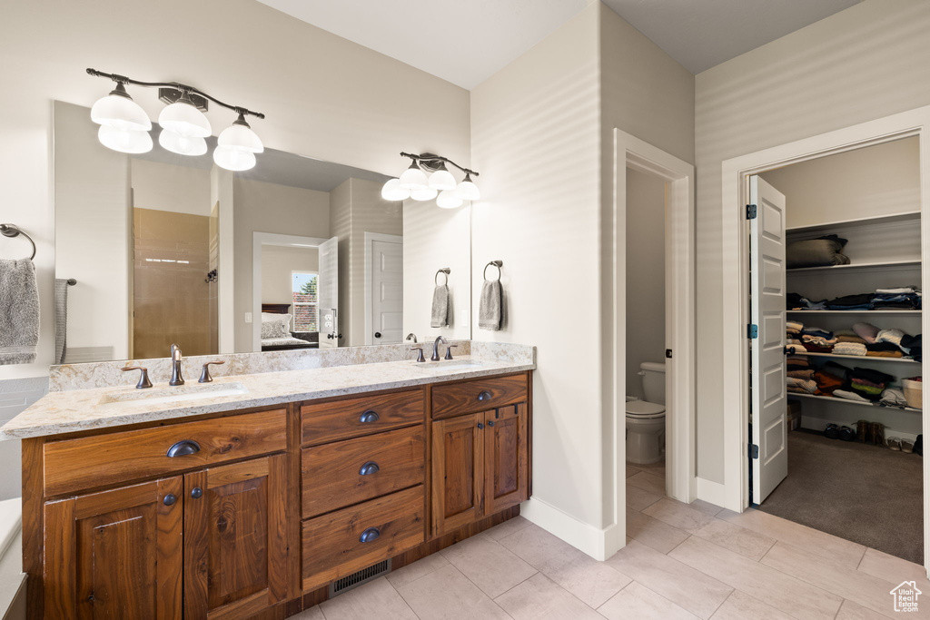 Full bath featuring double vanity, a shower, ensuite bath, and a walk in closet