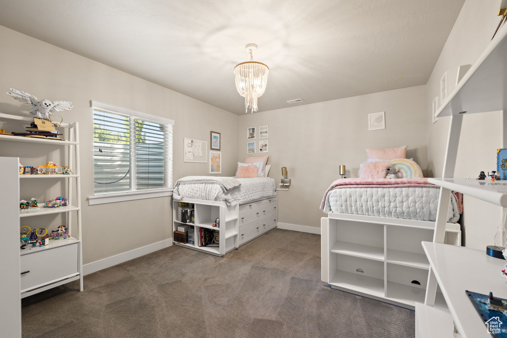 Carpeted bedroom featuring a chandelier and baseboards