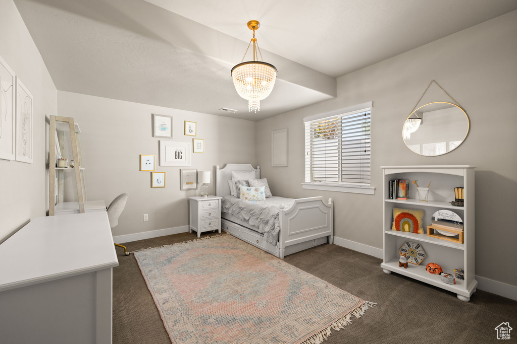 Bedroom with dark colored carpet and a chandelier