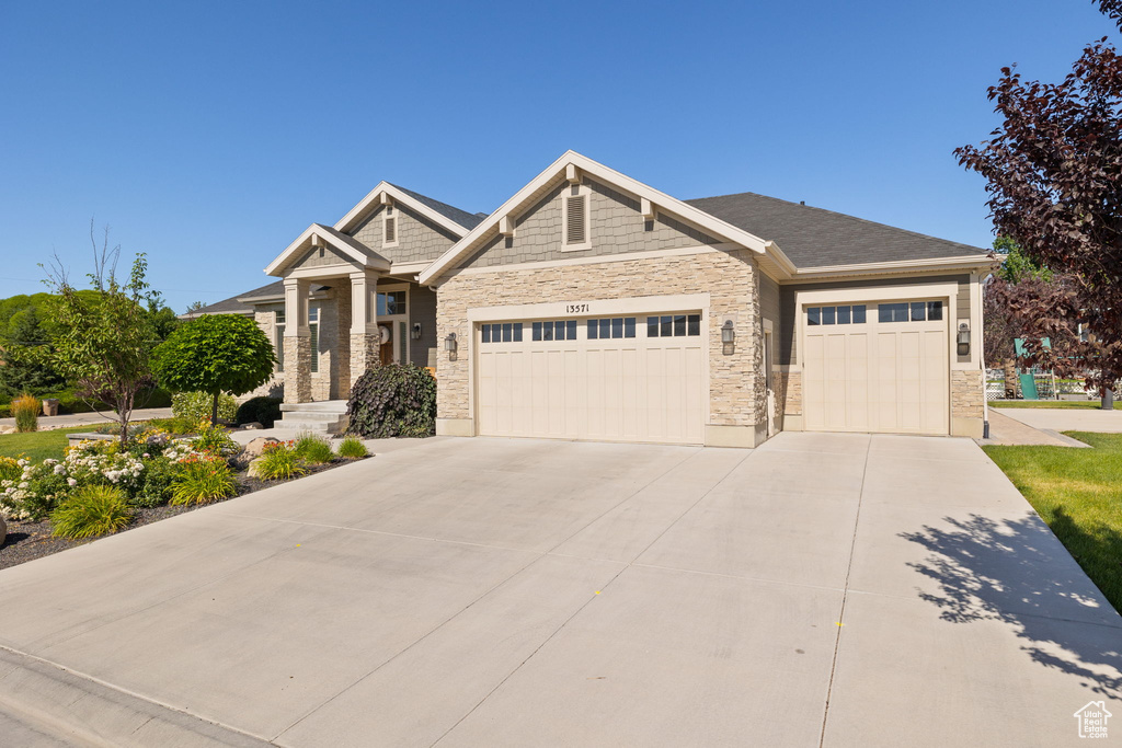 Craftsman inspired home with stone siding, an attached garage, and driveway