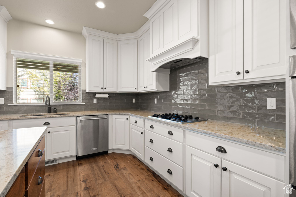 Kitchen with stainless steel appliances, dark wood-style flooring, white cabinets, tasteful backsplash, and recessed lighting