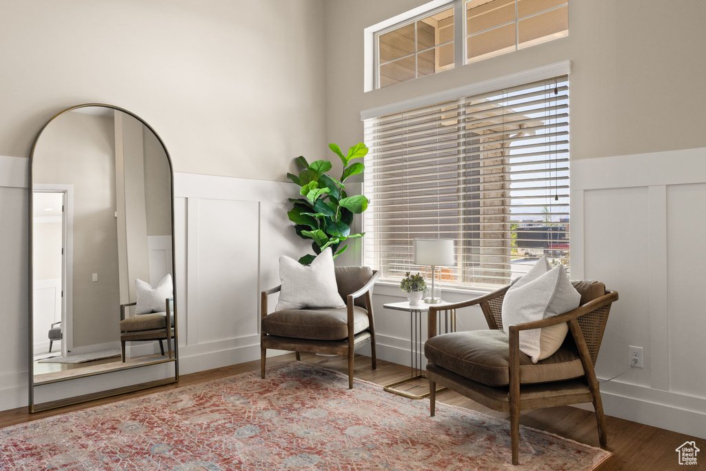 Sitting room with a decorative wall, wood finished floors, and wainscoting