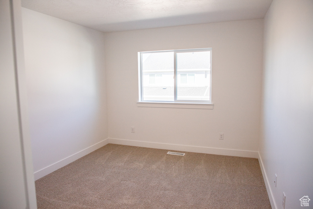 Unfurnished room featuring light carpet and baseboards