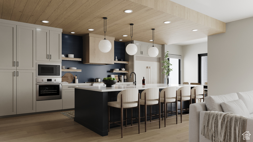 Kitchen featuring built in appliances, open shelves, light countertops, light wood-style floors, and recessed lighting