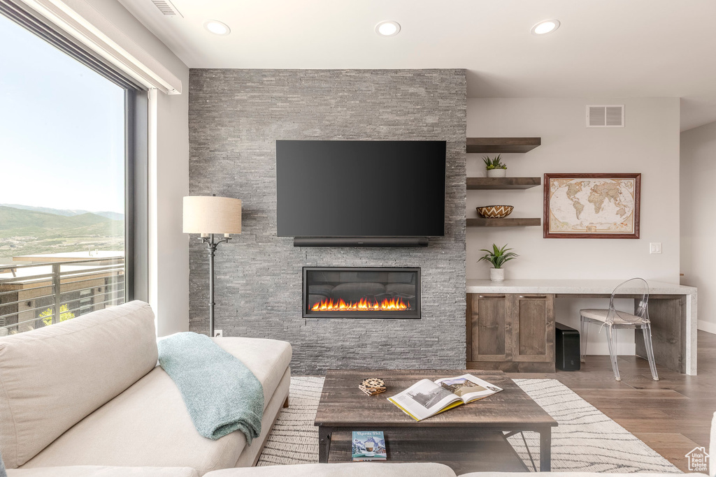 Living area with wood finished floors, recessed lighting, and a stone fireplace
