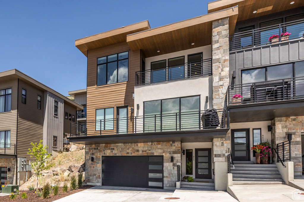 View of building exterior with an attached garage, driveway, and entry steps