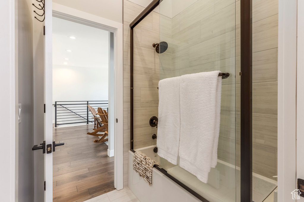 Full bathroom with bath / shower combo with glass door and wood finished floors