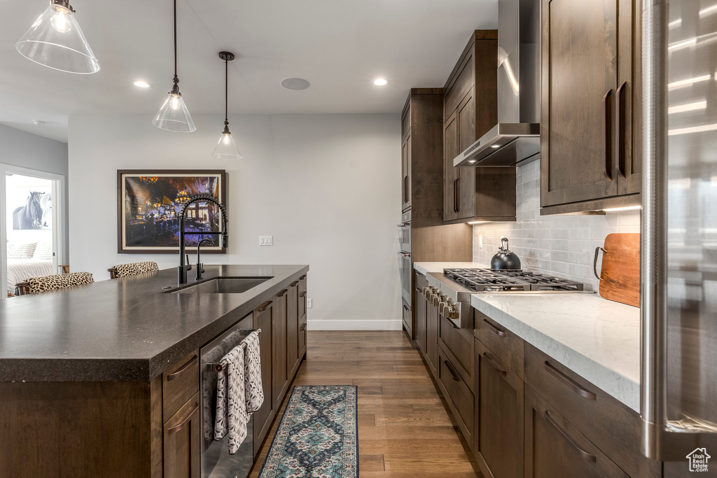 Kitchen with wall chimney exhaust hood, backsplash, dark wood finished floors, dark brown cabinets, and recessed lighting
