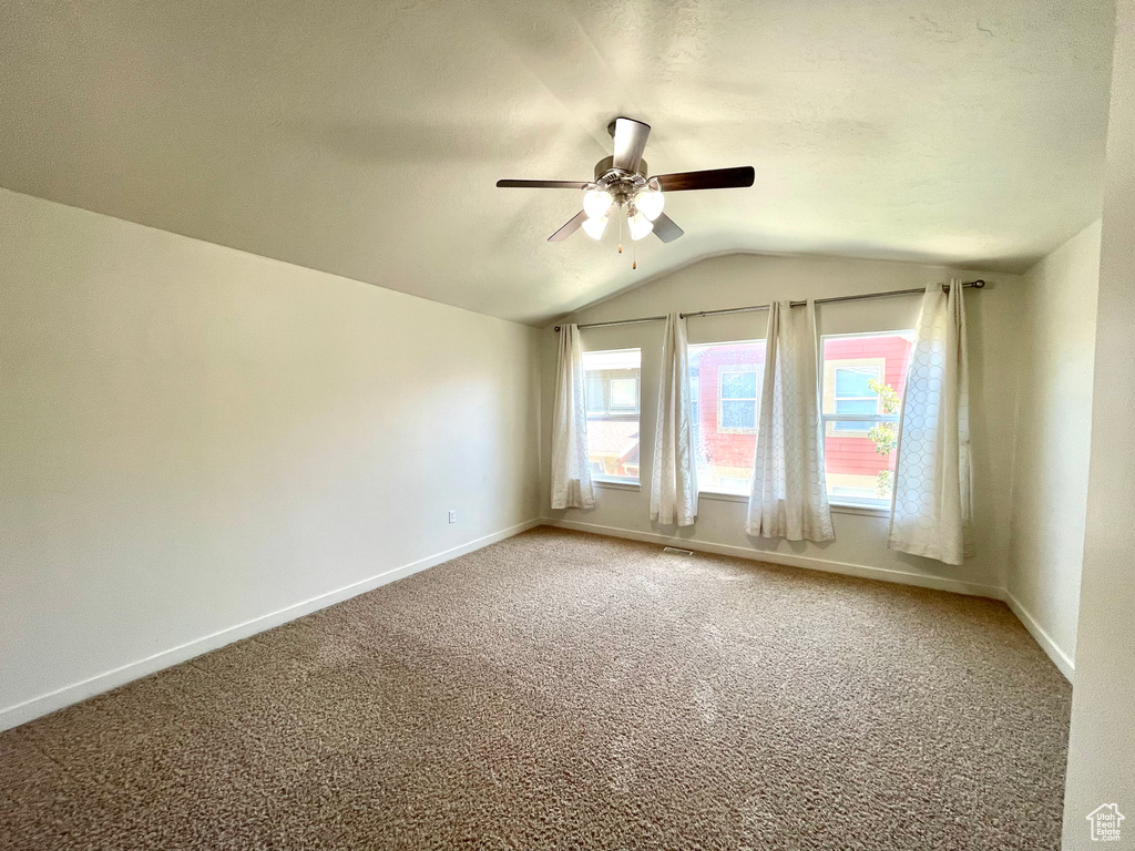 Spare room featuring ceiling fan, vaulted ceiling, and carpet
