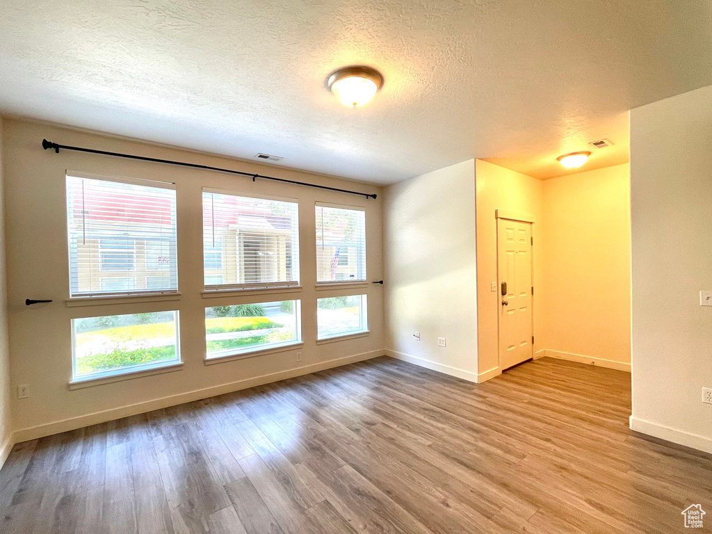 Unfurnished room with wood finished floors and a textured ceiling