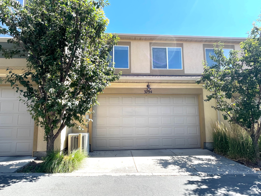 View of front of property featuring stucco siding, a garage, and driveway