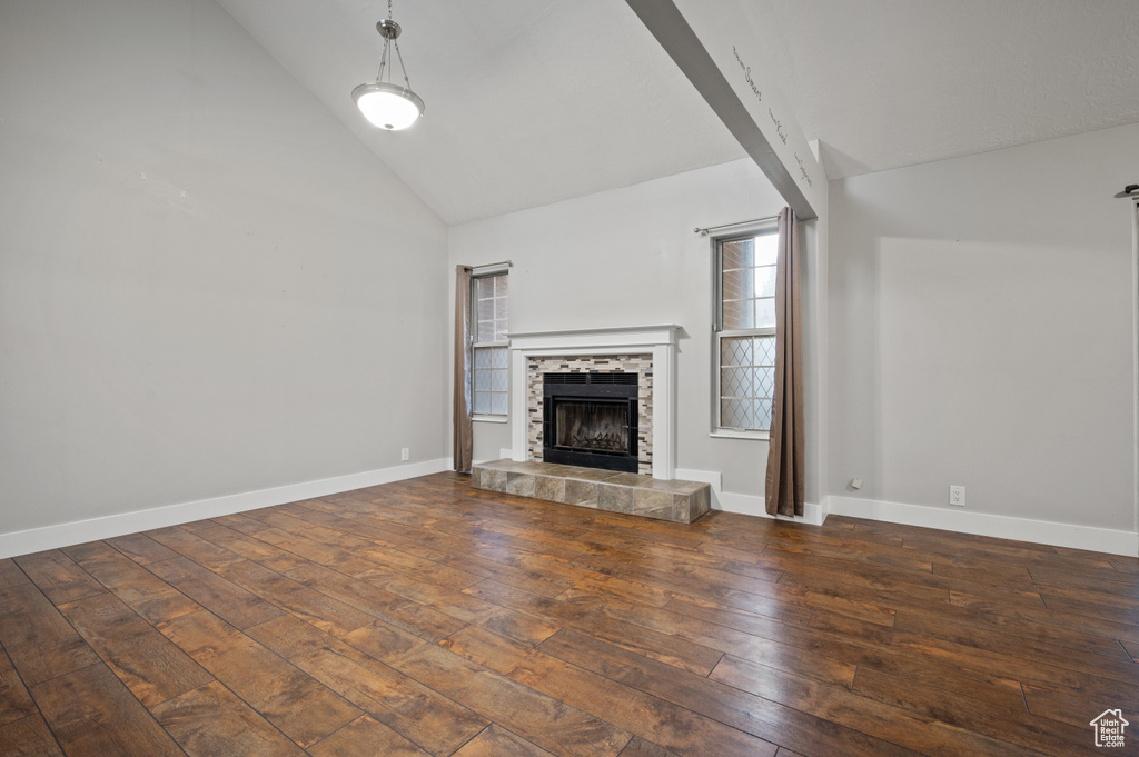 Unfurnished living room featuring wood-type flooring, a fireplace, and high vaulted ceiling