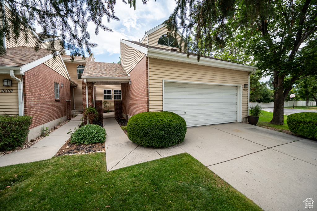 View of front of property featuring an attached garage, brick siding, concrete driveway, roof with shingles, and a front yard