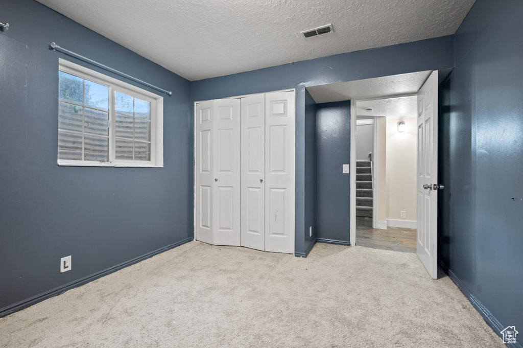 Unfurnished bedroom featuring carpet, a closet, and a textured ceiling