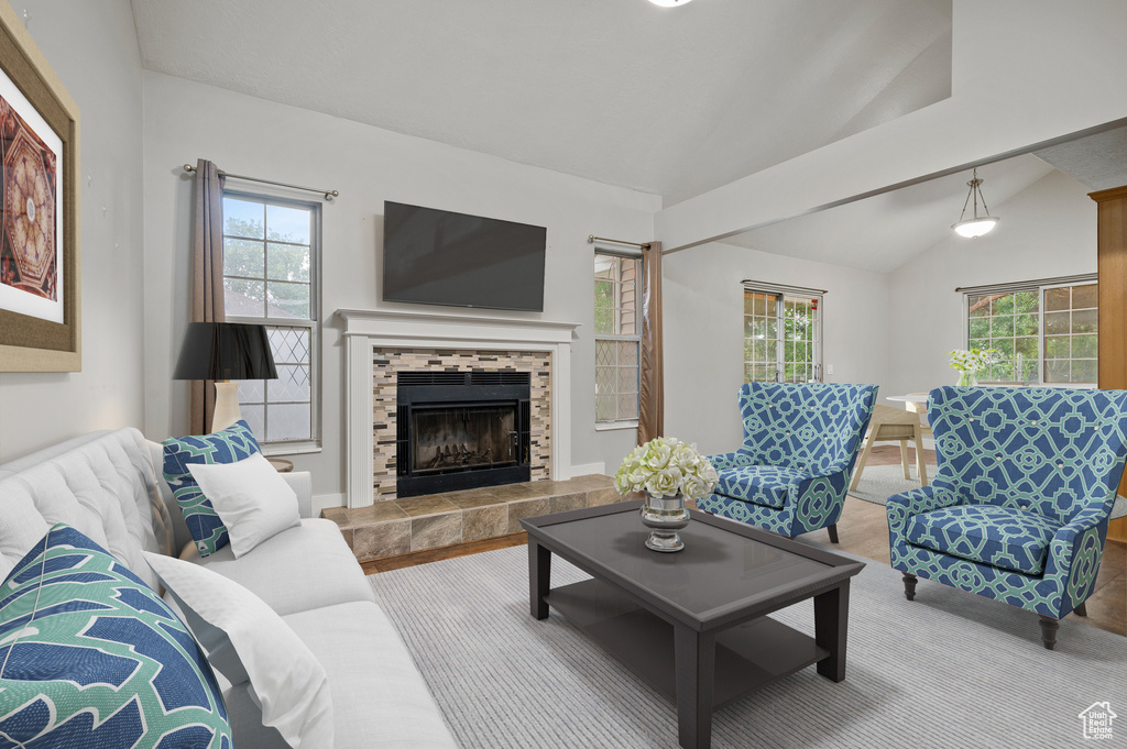 Carpeted living area with vaulted ceiling, healthy amount of natural light, and a fireplace
