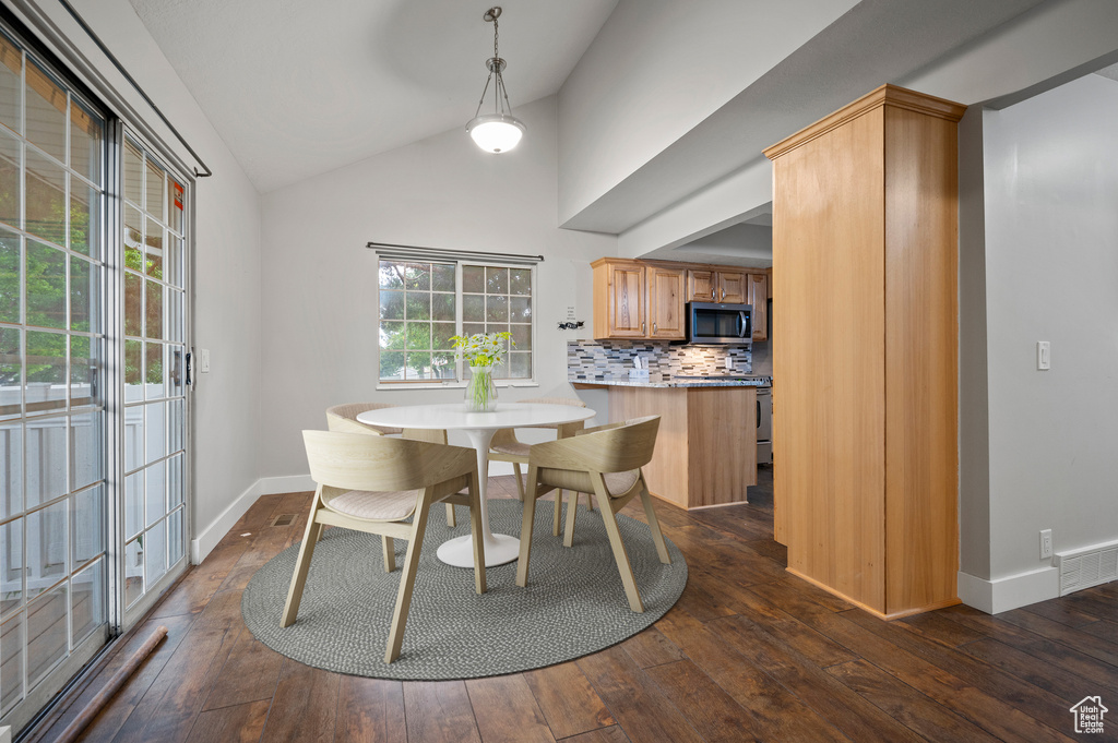 Dining area with dark wood-type flooring and high vaulted ceiling