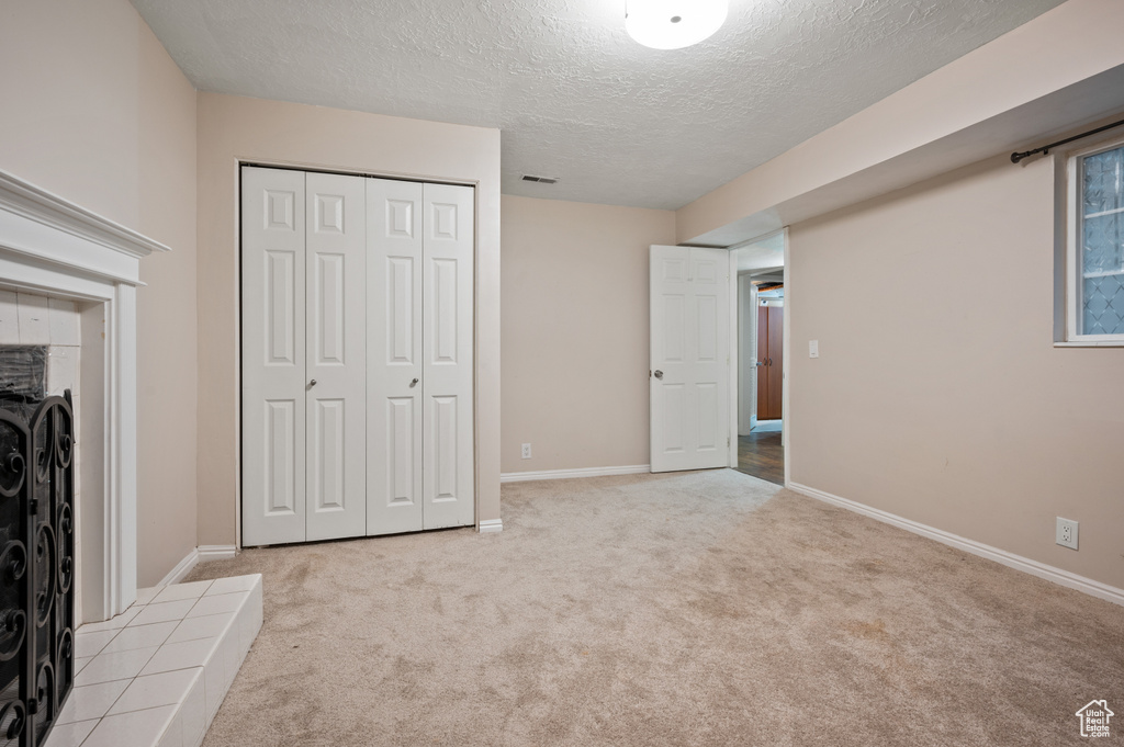 Unfurnished bedroom featuring light carpet, a textured ceiling, and a closet