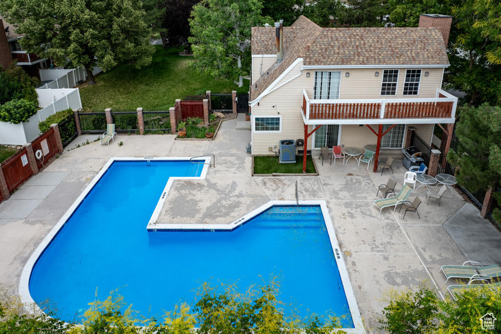 Community pool featuring a fenced backyard, a patio area, and view of scattered trees