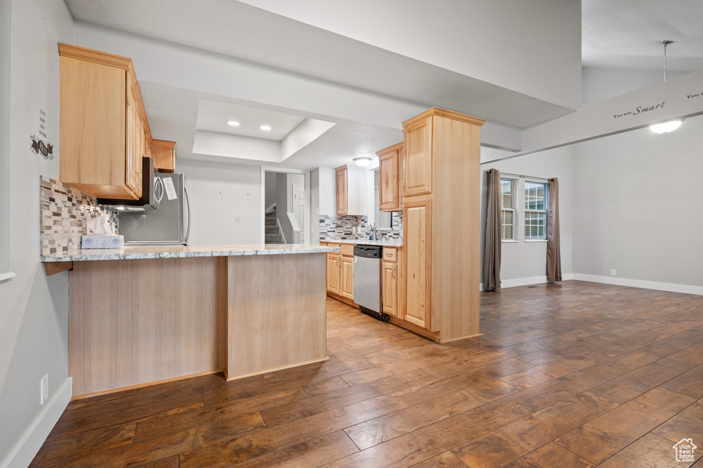 Kitchen featuring light brown cabinetry, stainless steel dishwasher, a peninsula, dark wood finished floors, and recessed lighting