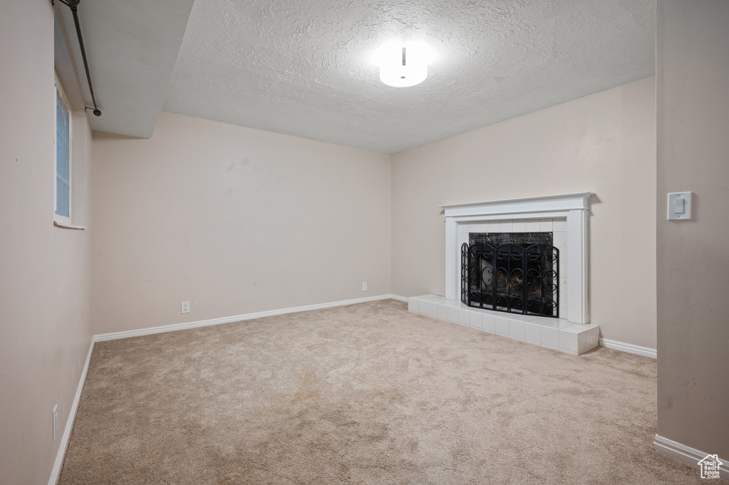 Unfurnished living room with a textured ceiling, carpet floors, and a fireplace