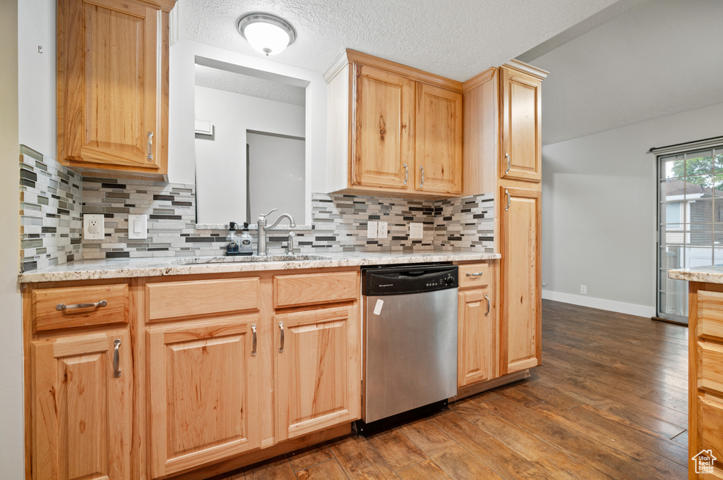 Kitchen featuring dishwasher, light brown cabinetry, dark wood-type flooring, backsplash, and a textured ceiling