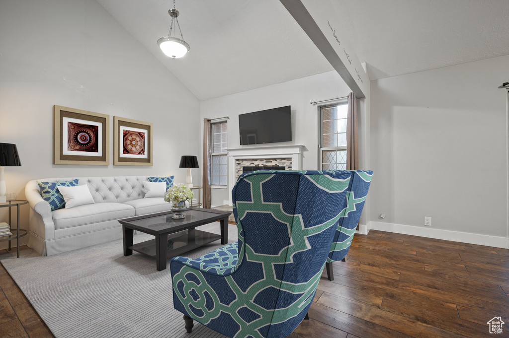 Living area featuring wood-type flooring, a tiled fireplace, and high vaulted ceiling