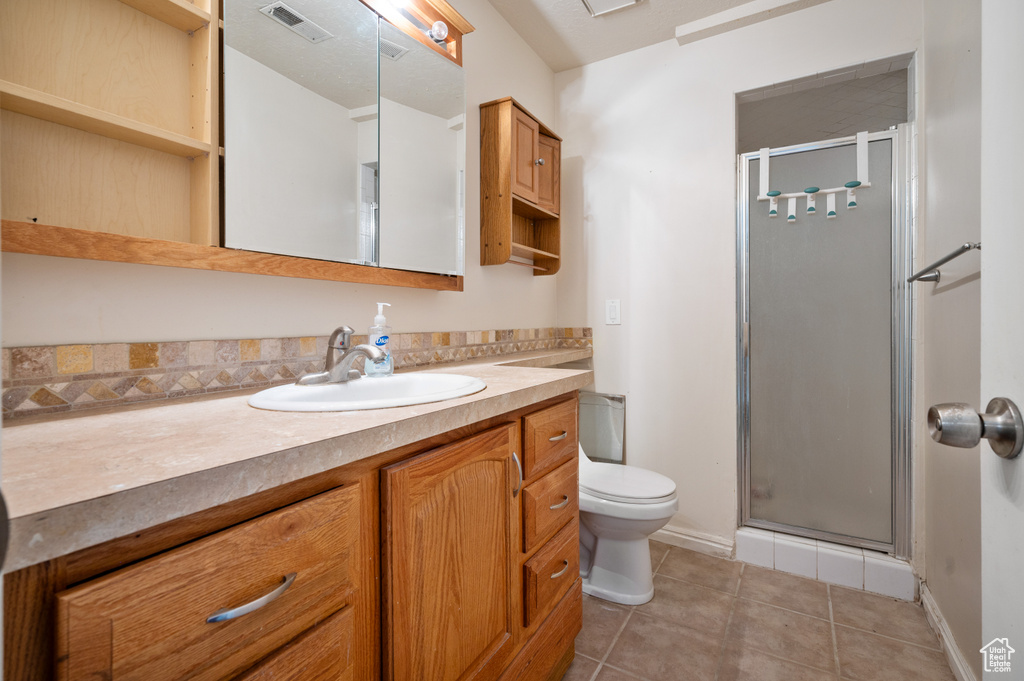 Full bath with vanity, a stall shower, and tile patterned floors