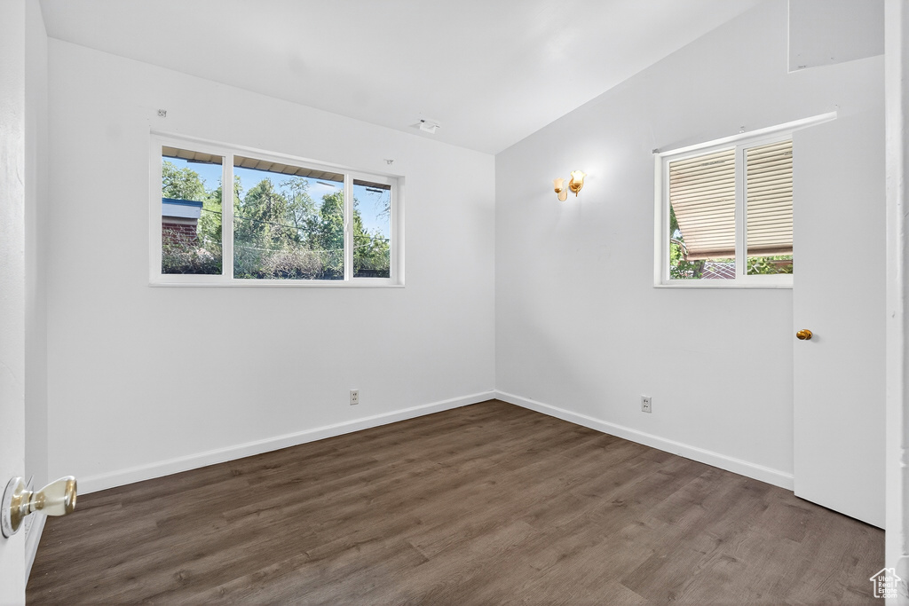 Unfurnished room with wood finished floors and lofted ceiling