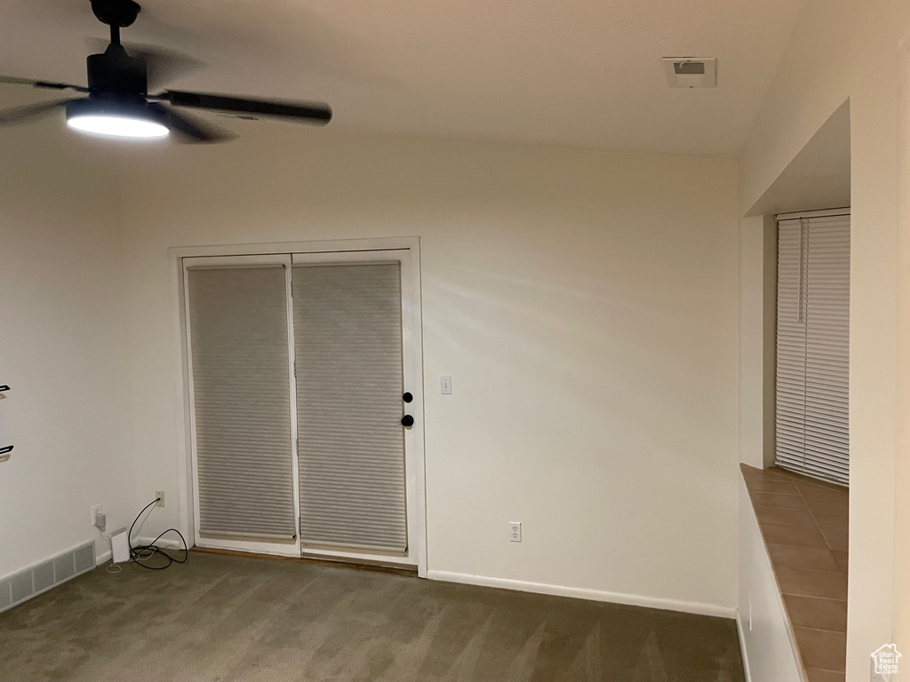 Empty room with a ceiling fan and carpet floors
