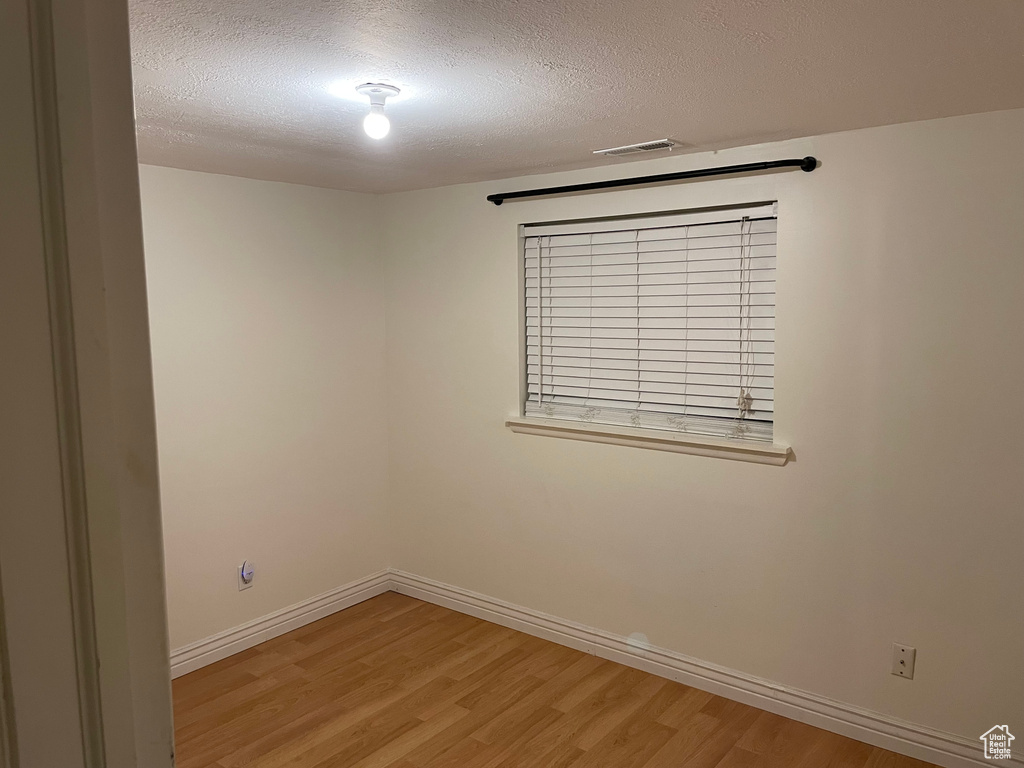 Empty room with light wood-style flooring and a textured ceiling
