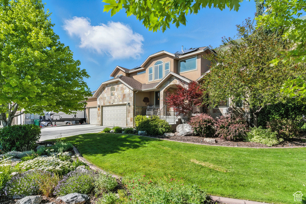 Traditional-style house with stone siding, stucco siding, a front lawn, and solar panels