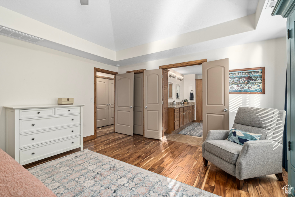 Bedroom featuring dark wood-style flooring, a towering ceiling, and ensuite bath