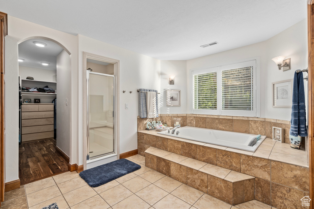 Bathroom with a stall shower, a garden tub, a walk in closet, and tile patterned flooring