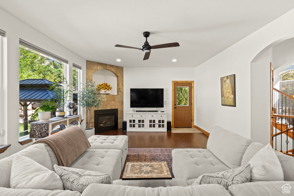 Living area with dark wood-type flooring, plenty of natural light, a ceiling fan, recessed lighting, and a fireplace