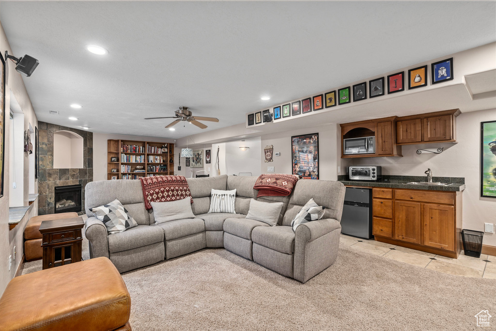 Living room with a tile fireplace, a ceiling fan, recessed lighting, light tile patterned floors, and wet bar
