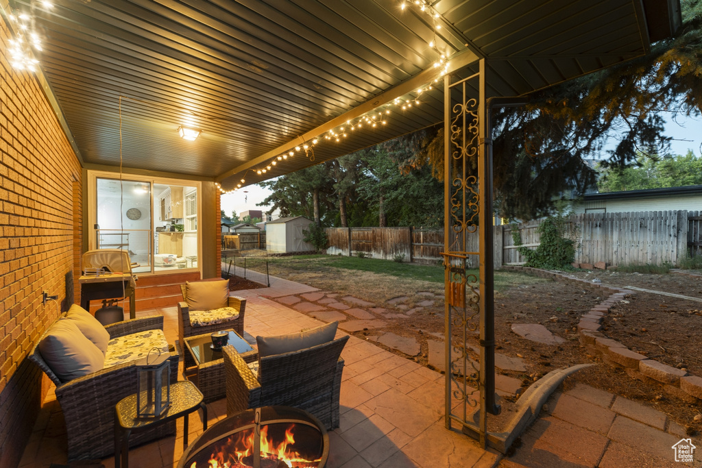 Fenced backyard with a patio, a storage unit, and an outdoor living space with a fire pit