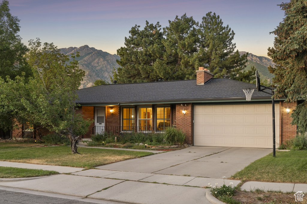 Ranch-style house with a garage, a mountain view, brick siding, and a yard