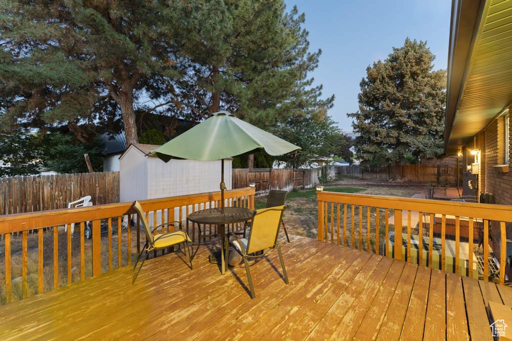 Wooden deck with a fenced backyard, outdoor dining area, and an outdoor structure